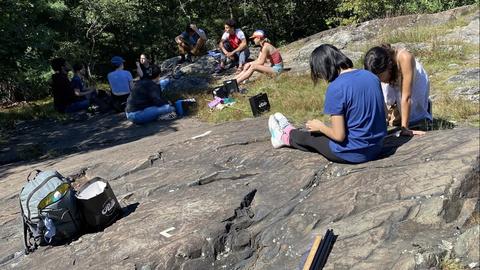 Students sitting on a large glacial rock.