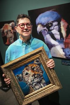 Older woman holding a painting.