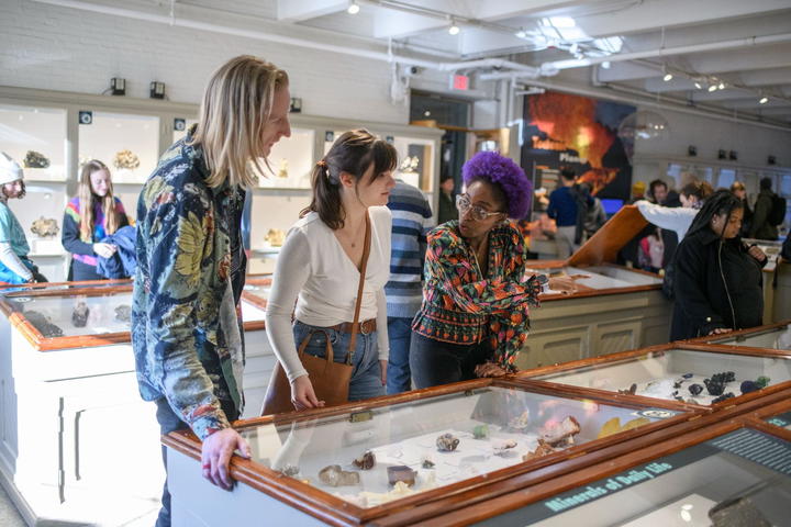 A group of people in the foreground pointing at objects in the gallery.