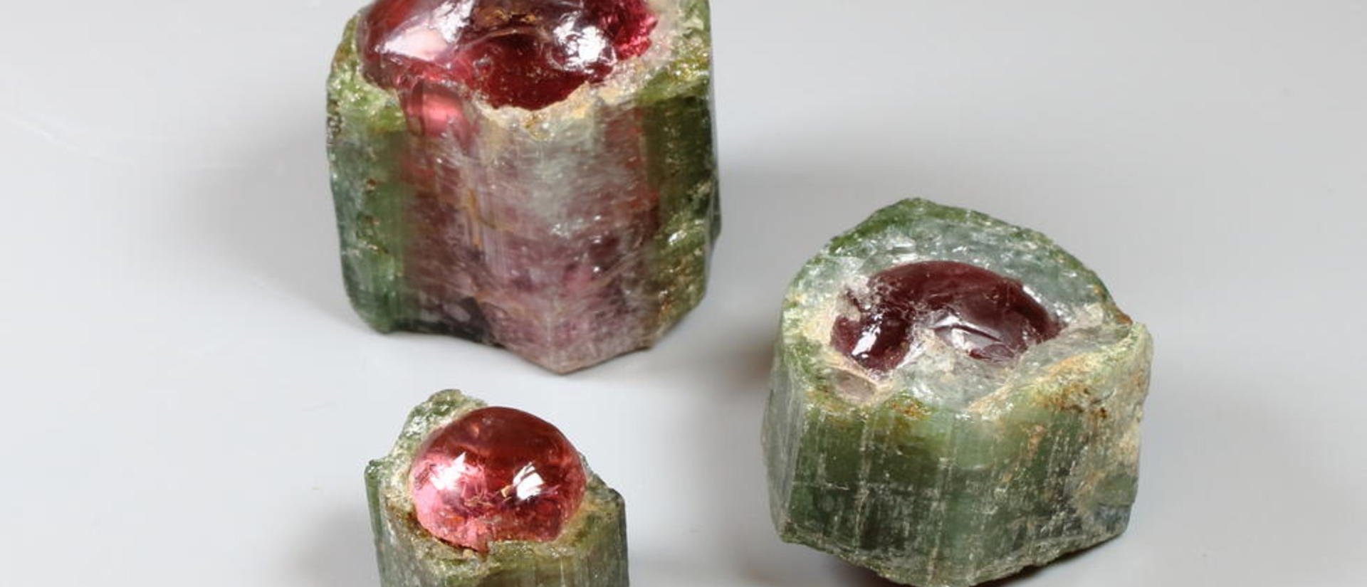 Three different sizes of green and pink tourmaline.