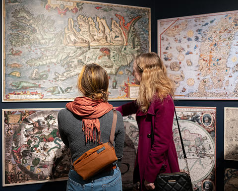 2 women look at maps in sea monsters gallery.