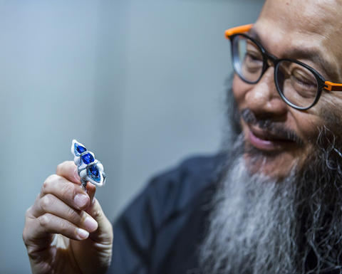 Artist Wallace Chan holding a brooch he made.