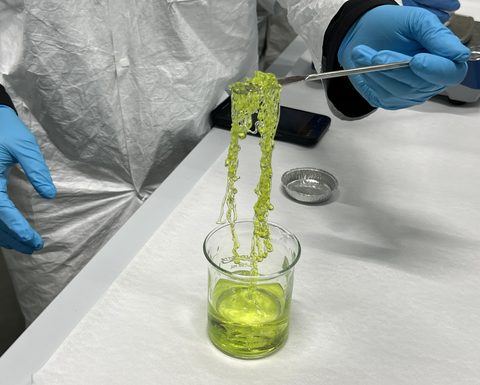 Lab equipment with slime being lifted out of it.