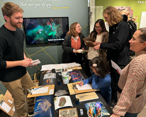 Several guests speaking to an expert at their table on Fossil Day.
