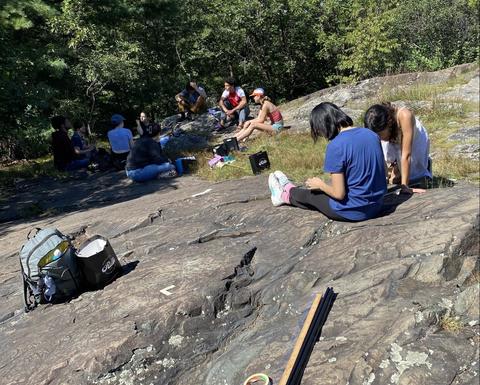 Students sitting on a large glacial rock.
